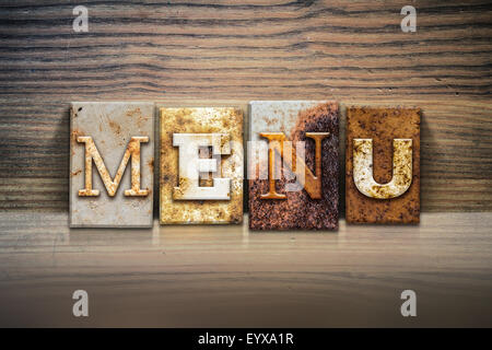 La parola 'MENU' scritto in metallo arrugginito rilievografia tipo seduto su un listello di legno dello sfondo. Foto Stock