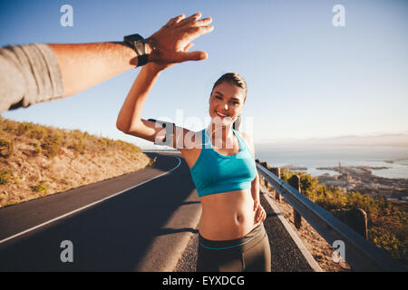 Montare la giovane donna dando alta cinque per il suo fidanzato dopo una corsa. POV shot di coppia elevata fiving sulla strada di campagna in mattina. Foto Stock