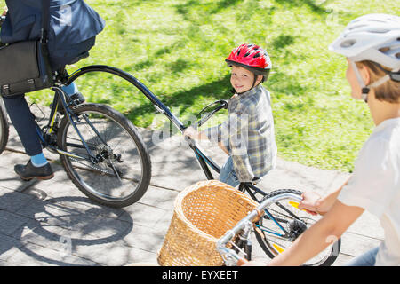 Ritratto sorridente ragazzo di equitazione Bicicletta in tandem con il padre nel parco Foto Stock