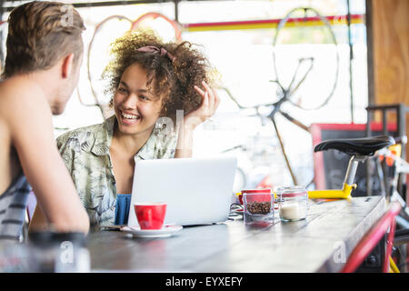 Paio di parlare al computer portatile in cafe Foto Stock