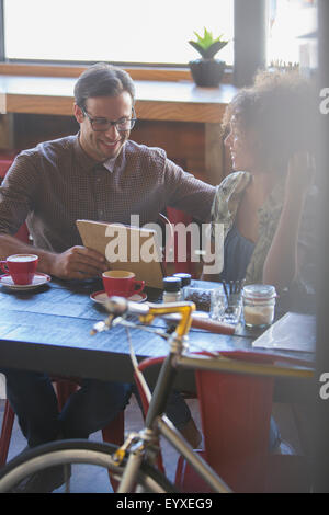 Amici di condivisione digitale compressa in cafe Foto Stock