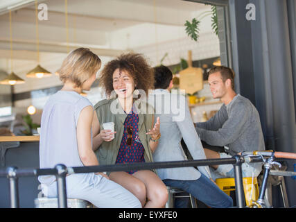 Ridere amici appendere fuori a bere caffè sul patio cafe Foto Stock