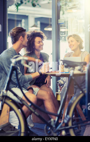 Amici appendere fuori al tavolo del bar dietro la bicicletta Foto Stock