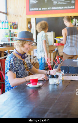 Donna in hat usando tavoletta digitale presso il cafe Foto Stock