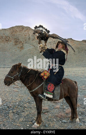 Il kazako eagle cacciatore con il suo ONU-incappucciati golden eagle tenuto alta #1, a ovest di Olgii, Mongolia occidentale Foto Stock