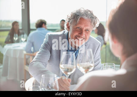 Coppia sorridente bere il vino nel ristorante soleggiato Foto Stock