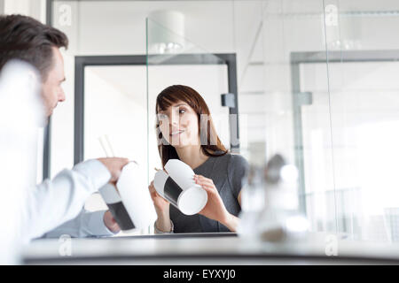 Imprenditore e imprenditrice cinese di mangiare cibo asporto in office caff Foto Stock