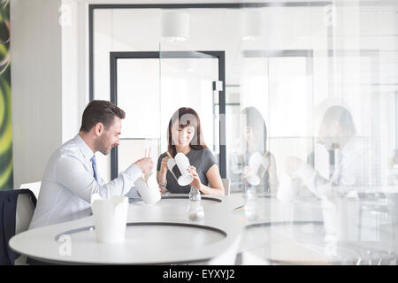 Imprenditore e imprenditrice cinese di mangiare cibo asporto in office caff Foto Stock