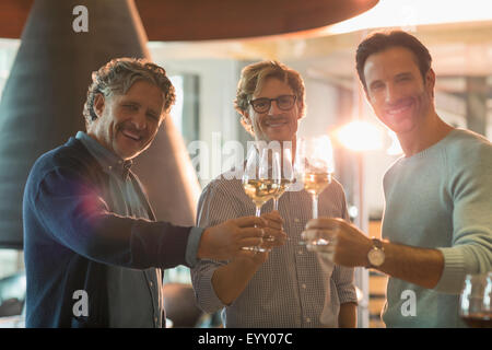 Ritratto uomini sorridenti di bere il vino bianco in cantina Foto Stock