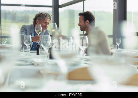 Gli uomini la tostatura bicchieri di vino al ristorante tabella Foto Stock