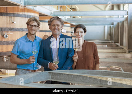 Ritratto sorridente vintners con vino bianco in cantina Foto Stock