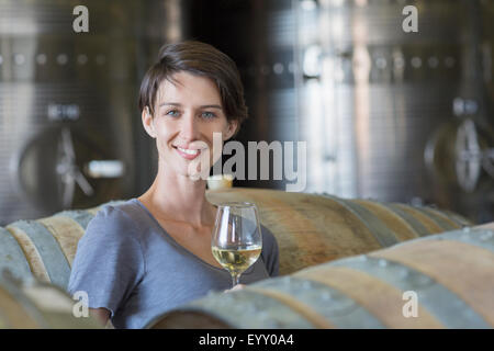 Ritratto fiducioso vignaiolo di bere vino bianco in cantina Foto Stock