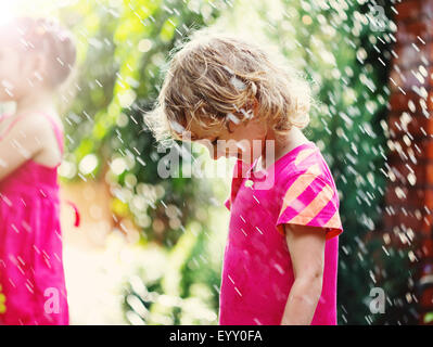 Felice carino bambina in piedi sotto la pioggia. Close up ritratto. Foto Stock