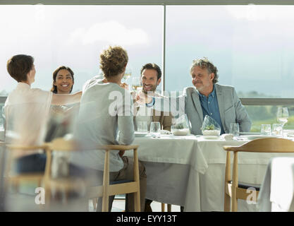 Amici tostatura di bicchieri di vino al ristorante soleggiato tabella Foto Stock