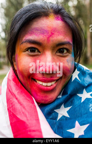 Sorridente donna asiatica coperti di polvere di pigmento indossando bandiera americana Foto Stock