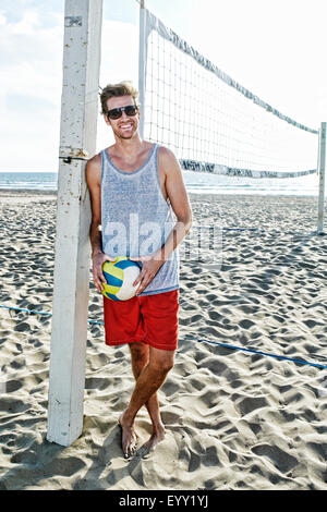 Uomo caucasico holding pallavolo sulla spiaggia Foto Stock