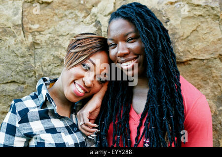 Donna sorridente abbracciando vicino a parete di roccia Foto Stock