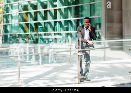 Imprenditore nero parlando al cellulare all'esterno dell'edificio Foto Stock