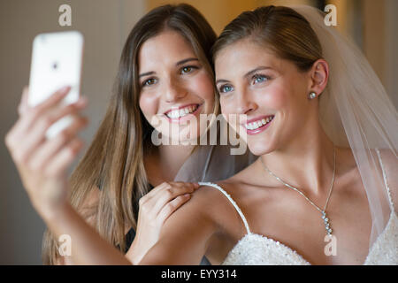 Sposa caucasica e damigella tenendo selfie Foto Stock