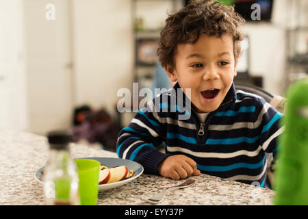 Razza mista ragazzo di mangiare al bancone cucina Foto Stock