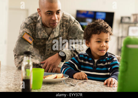 Razza mista soldato padre e figlio di mangiare in cucina Foto Stock