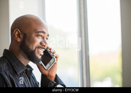 Uomo nero parlando al cellulare vicino a finestra Foto Stock