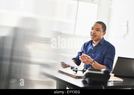 Imprenditore nero parlando a scrivania da ufficio Foto Stock