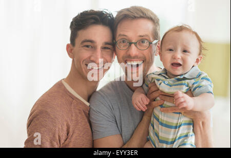 Sorridente caucasica padri gay holding baby Foto Stock