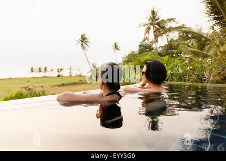 Donne ammirando scenic vista in piscina infinity Foto Stock