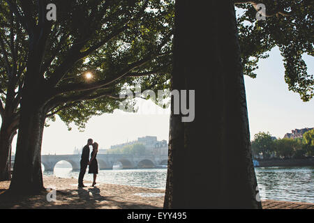 Coppia caucasica kissing vicino a ponte, Parigi, Ile-de-France, Francia Foto Stock