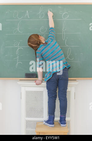 Ragazza caucasica scrivere sulla lavagna in aula Foto Stock