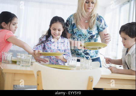 Caucasian madre e bambini nella tabella di impostazione Foto Stock