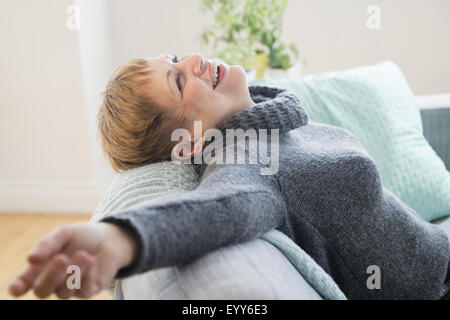 Ridendo donna caucasica la posa sul divano Foto Stock