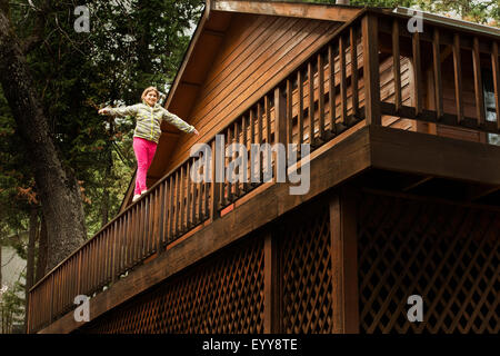 Razza mista ragazza in equilibrio su una ringhiera di balcone Foto Stock