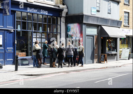 Una guida turistica con un gruppo di turisti a piedi intorno al Brick Lane, Shoreditch area di East London guardando i pezzi di graffiti Foto Stock