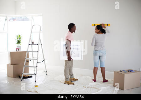 Giovane utilizza il livello nella nuova casa Foto Stock