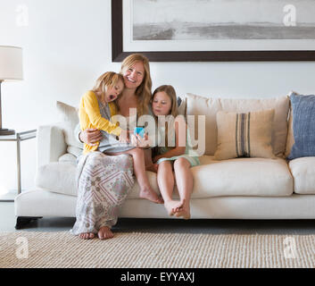 Caucasian la madre e le figlie tramite telefono cellulare sul divano Foto Stock