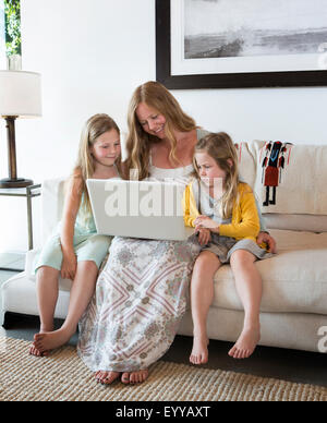 Caucasian la madre e le figlie utilizzando computer portatile sul divano Foto Stock