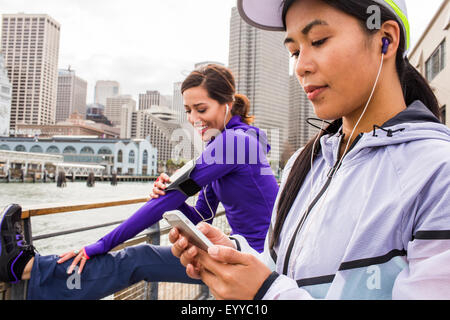 Runner tramite telefono cellulare a waterfront, San Francisco, California, Stati Uniti Foto Stock