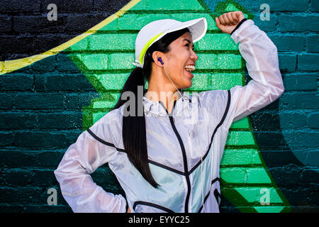 Asian runner in piedi vicino al muro di graffiti Foto Stock