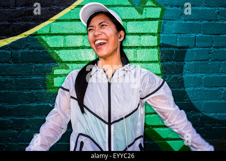 Asian runner in piedi vicino al muro di graffiti Foto Stock