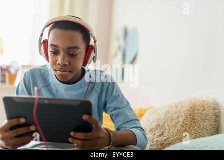 Black Boy in cuffie utilizzando tavoletta digitale Foto Stock