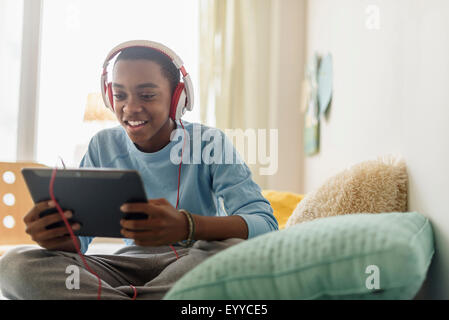 Black Boy in cuffie utilizzando tavoletta digitale Foto Stock