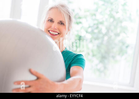 I vecchi donna caucasica tenendo palla ginnica in palestra Foto Stock