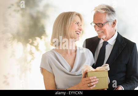 Sorridente vecchio uomo caucasico dando moglie un regalo Foto Stock