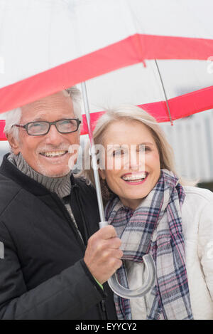 I vecchi Caucasian giovane in piedi sotto ombrellone Foto Stock