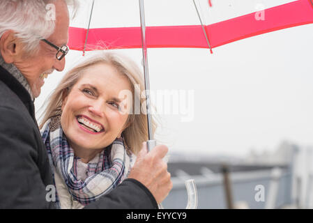 I vecchi Caucasian giovane in piedi sotto ombrellone Foto Stock