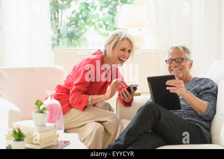 I vecchi Caucasian giovane utilizzando la tecnologia in salotto Foto Stock
