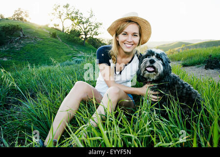 La donna caucasica petting cane nel campo Foto Stock