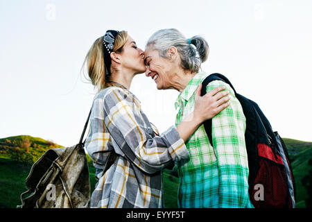 Figlia caucasica kissing madre sulla collina rurale Foto Stock